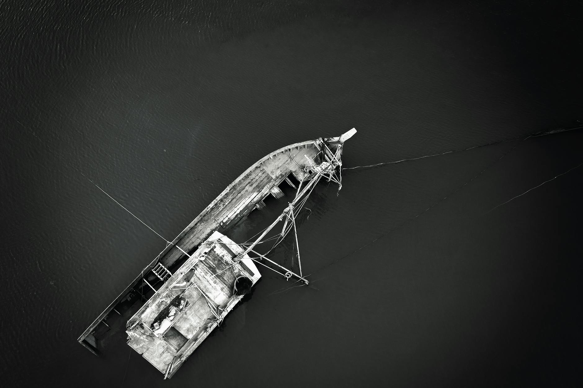 a grayscale of a sinking boat