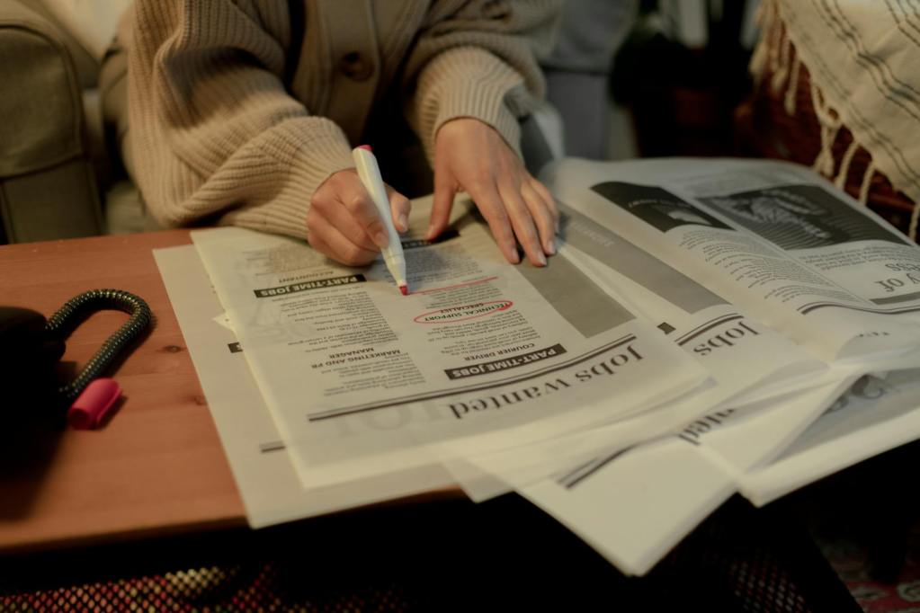close up on woman s hand while searching for job postings in newspaper